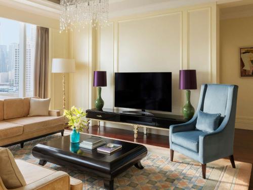 a living room with a television and a blue chair at Raffles Makati in Manila