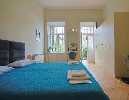 a bedroom with a blue bed with towels on it at Old and modern Apart Ninoshvili in Tbilisi City