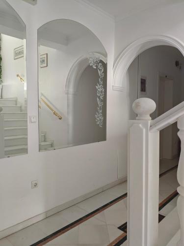a white hallway with a mirror and stairs at Ioli Apartments in Limenas