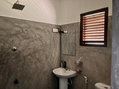 a bathroom with a sink and a toilet and a mirror at Melon Guest - Weligama in Weligama