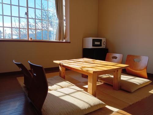 a dining room with a wooden table and chairs at Hostel SAMURISE NORTH in Fujikawaguchiko