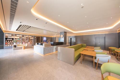 a lobby with a green couch and tables and chairs at JI Hotel Shanghai Caohejing Caobao Road in Shanghai