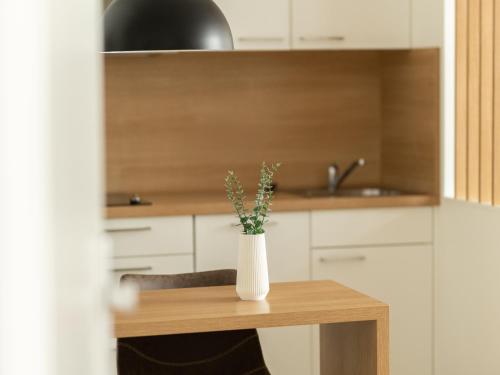 a white vase with flowers on a table in a kitchen at Haus NordQuartier in Norderney