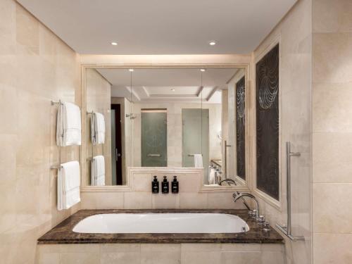 a bathroom with a tub and a large mirror at Raffles Makkah Palace in Makkah