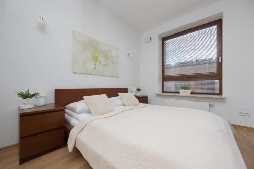 a white bedroom with a large bed and a window at Spacious and Bright Apartment with Parking in the City Center by Noclegi Renters in Warsaw