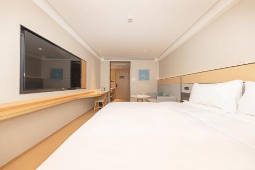 a bedroom with a large white bed and a large flat screen tv at JI Hotel Shanghai Caohejing Caobao Road in Shanghai