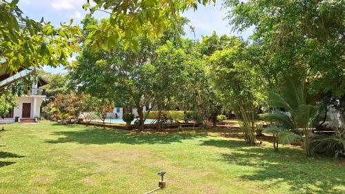 a yard with trees and benches in front of a house at Four Points Resort - Anuradhapura in Anuradhapura