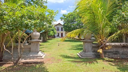 a garden with palm trees and a house in the background at Four Points Resort - Anuradhapura in Anuradhapura