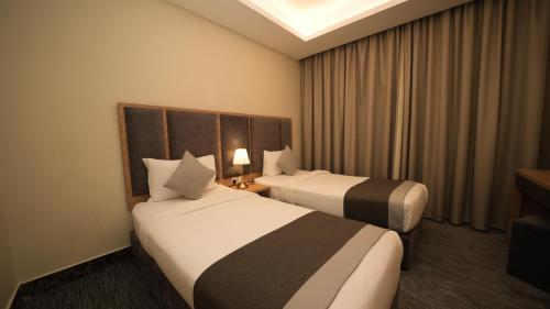 a hotel room with two beds and a window at بنزرت للشقق المخدومة in Al Hofuf