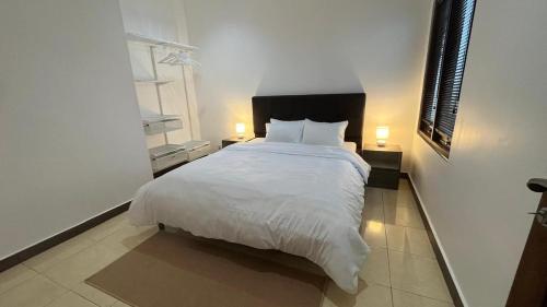 a bedroom with a large white bed with two lamps at Schonen House by Ruby Living in Yogyakarta