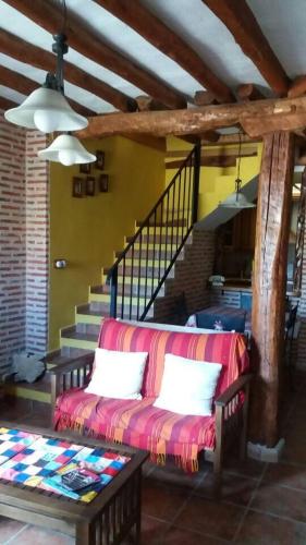 a living room with a couch and a staircase at Casa Rural Hoces del Duratón El Villar in Villar de Sobrepeña