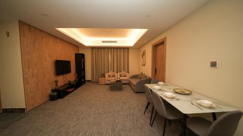 a hotel room with tables and chairs and a living room at بنزرت للشقق المخدومة in Al Hofuf
