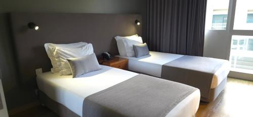 a hotel room with two beds and a window at Apartamentos Turisticos Paraiso in Funchal