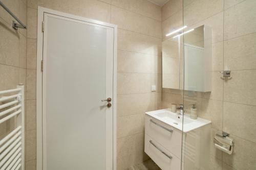 a white bathroom with a sink and a mirror at TRINAVIS Boutique Apartments, OWN PRIVATE PARKING, City Center, Entire Apartment in Veliko Tŭrnovo