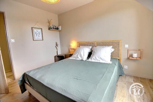 a bedroom with a bed with blue sheets and white pillows at Le petit duc in Langast