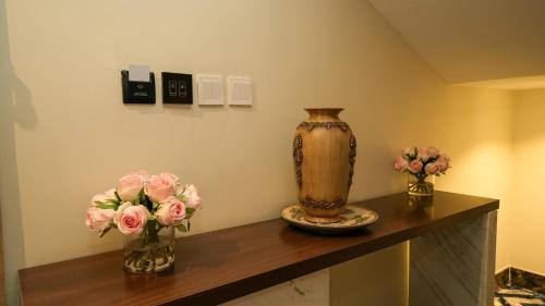 a table with two vases and flowers on it at بنزرت للشقق المخدومة in Al Hofuf