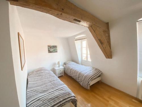 Colmar Attic Duplex في كولمار: سريران في غرفة ذات جدران بيضاء وأسقف خشبية