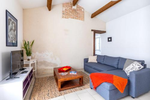 Una sala de estar con un sofá azul y un televisor. en Entre Terre et Sel - Centre Bouin - Wifi, en Bouin