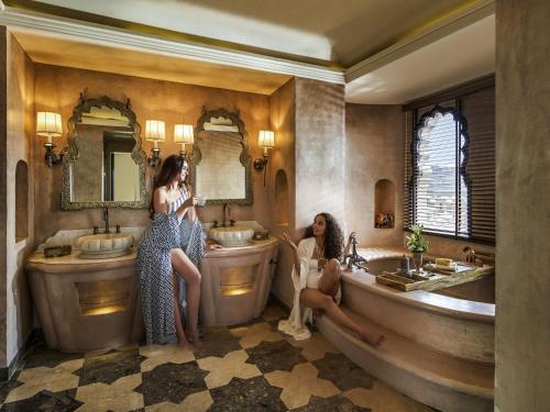 two women sitting in a bathroom with two sinks at Fairmont Jaipur in Jaipur