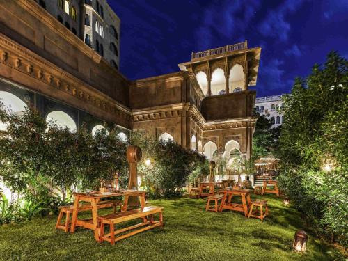 a patio with wooden tables and benches in a yard at Fairmont Jaipur in Jaipur