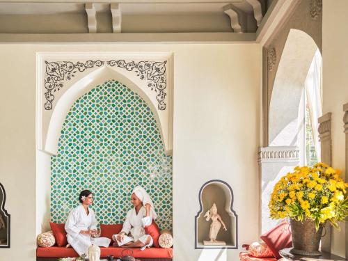 two people sitting on a couch in a room with a wall at Fairmont Jaipur in Jaipur