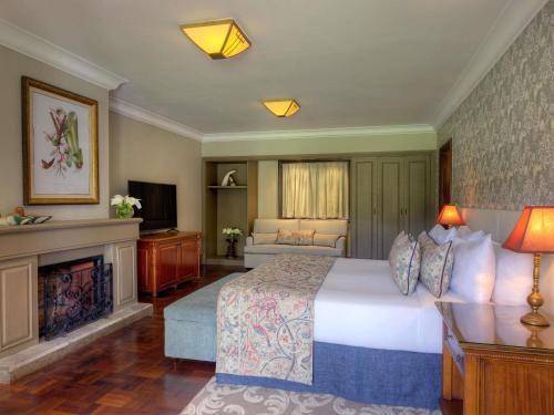a bedroom with a large bed and a fireplace at Fairmont Mount Kenya Safari Club in Nanyuki