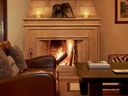 a fireplace with an elephant statue in a living room at Fairmont Mount Kenya Safari Club in Nanyuki