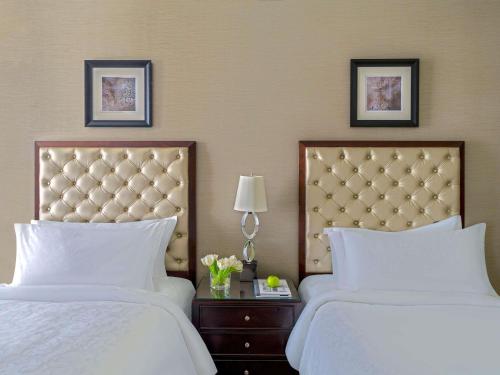 two beds in a hotel room with white sheets at Makkah Clock Royal Tower, A Fairmont Hotel in Makkah