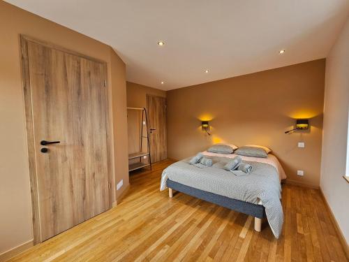 a bedroom with a bed and a wooden floor at L'Escargot - Maison avec espace bien être in Vagney