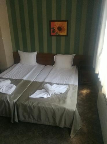 a bed with white sheets and towels on it at Hotel St. George Pobedonosets in Bansko