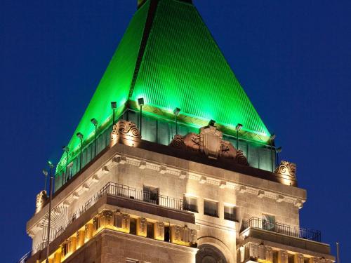 a building is lit up in green at night at Fairmont Peace Hotel on the Bund in Shanghai