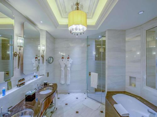a bathroom with two sinks and a tub and a chandelier at Fairmont Peace Hotel on the Bund in Shanghai