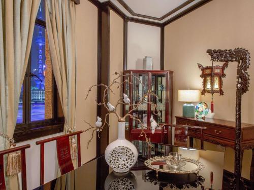 a room with a table with a vase and a mirror at Fairmont Peace Hotel on the Bund in Shanghai