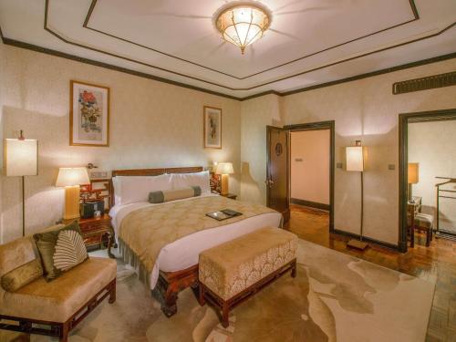 a bedroom with a large bed and two chairs at Fairmont Peace Hotel on the Bund in Shanghai