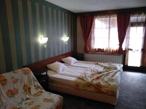 a hotel room with two beds and a chair at Hotel St. George Pobedonosets in Bansko
