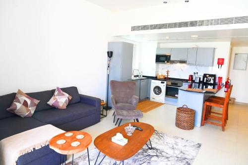 a living room with a blue couch and a kitchen at Wateera Jebel Sifah in As Sīfah