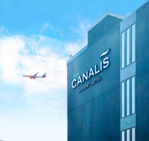 a plane is flying over a building with a sign at Canalis Suvarnabhumi Airport Hotel - Free Scheduled shuttle from Hotel to Suvarnabhumi Airport in Lat Krabang