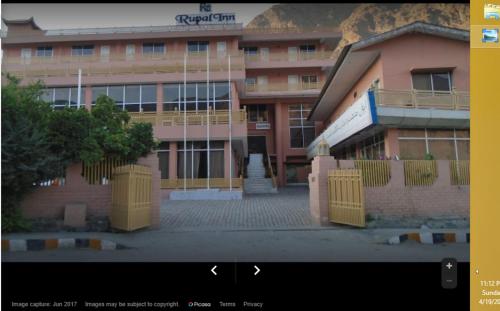 a building with yellow gates in front of a building at Rupal Inn in Dargai