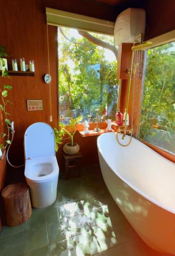 a bathroom with a tub and a toilet and a window at Nhà Bên Đồi in Thôn Dương Phẩm