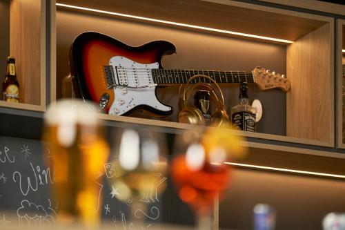 a guitar is sitting on a shelf with a beer at ibis Chur in Chur