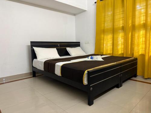 a bed in a room with yellow curtains at Bliss stays in Cochin