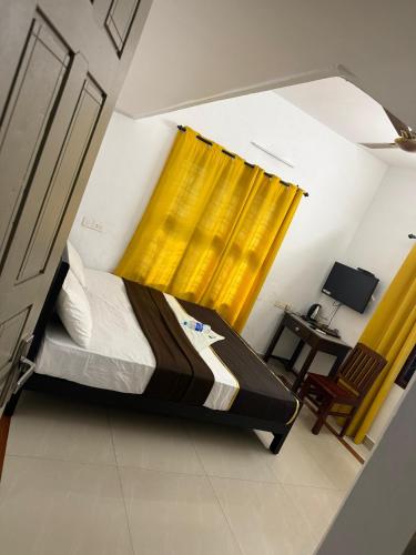 a bedroom with a bed with a yellow curtain at Bliss stays in Cochin
