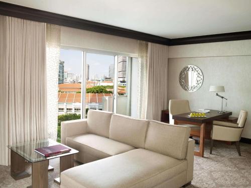 a living room with a couch and a table and a window at Fairmont Singapore in Singapore
