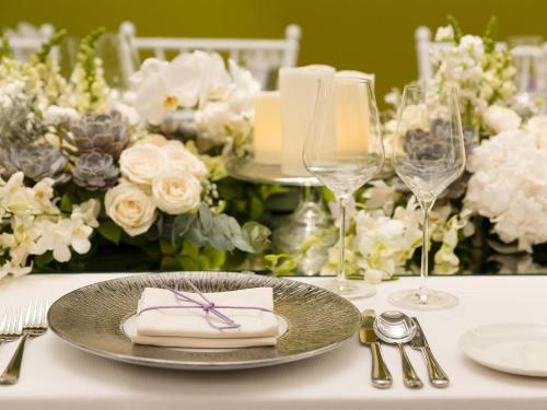 a table with a plate and glasses and flowers at Raffles Jakarta in Jakarta