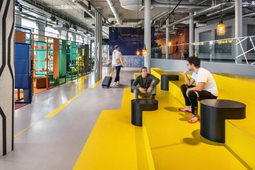 three people sitting on a yellow floor in an office at The Social Hub Delft Extended Stay in Delft