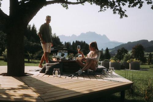 a woman sitting at a picnic table with a glass of wine at Farm Hotel Chalet Grosslehen in Fieberbrunn