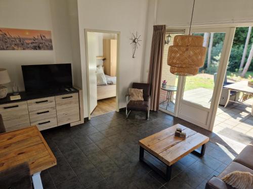 a living room with a couch and a tv and a table at Huinerhofje 3 - Vrijstaand, grote tuin, rust en veel privacy nabij uitgestrekte bossen in Putten