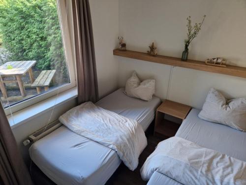 two beds in a room with a window at Huinerhofje 3 - Vrijstaand, grote tuin, rust en veel privacy nabij uitgestrekte bossen in Putten