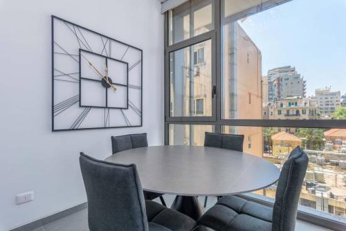 a dining room with a table and chairs and a clock at Sketch - Innovative 1-BR Apt by Convivium IX in Monot in Sodeco