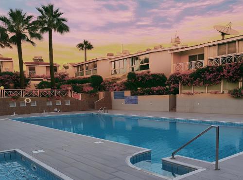 a swimming pool in front of a building with palm trees at Sea view Beach House with Pool in Limassol